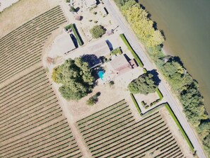An aerial view of a vineyard with rows of grapevines, a swimming pool, and a building with a distinct roof. - 
2-bedroom apartment in welcoming Saint-Pey-de-Castets close to Saint Emilion (Saint-Pey-de-Castets)