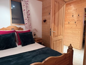 Un lit en bois avec une tête de lit, une table de chevet avec une lampe et une armoire avec des crochets.