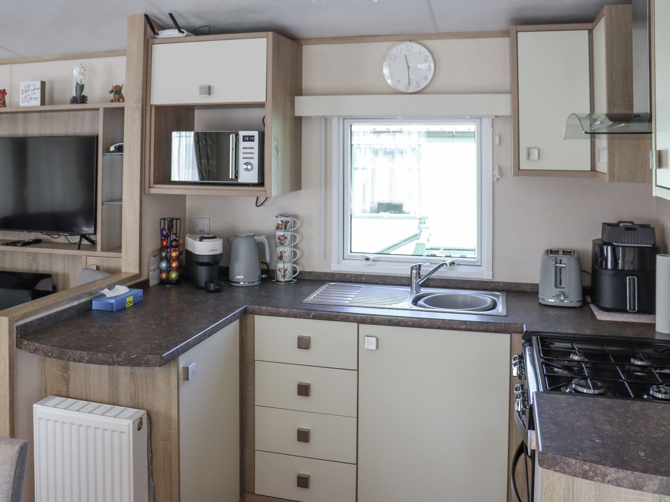 A compact kitchenette with a microwave, coffee maker, toaster, and a gas stove.