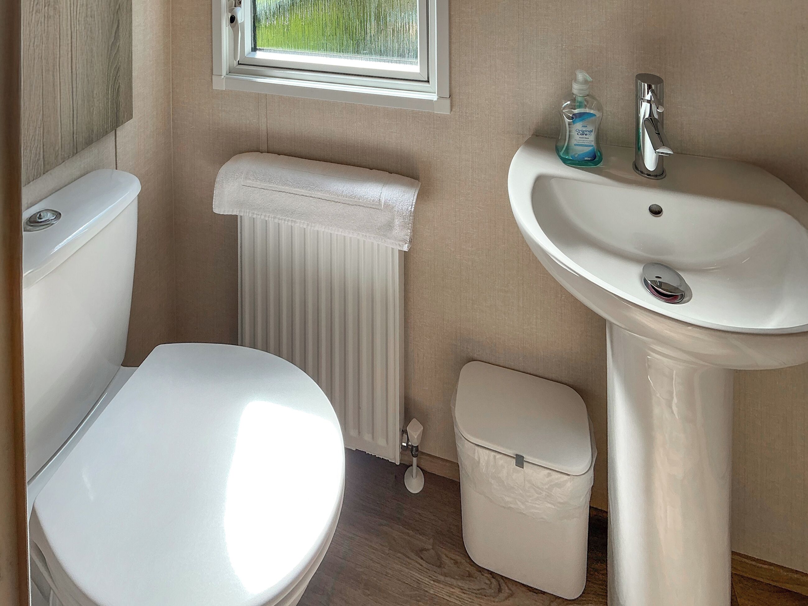 A bathroom with a toilet, a sink, and a window.