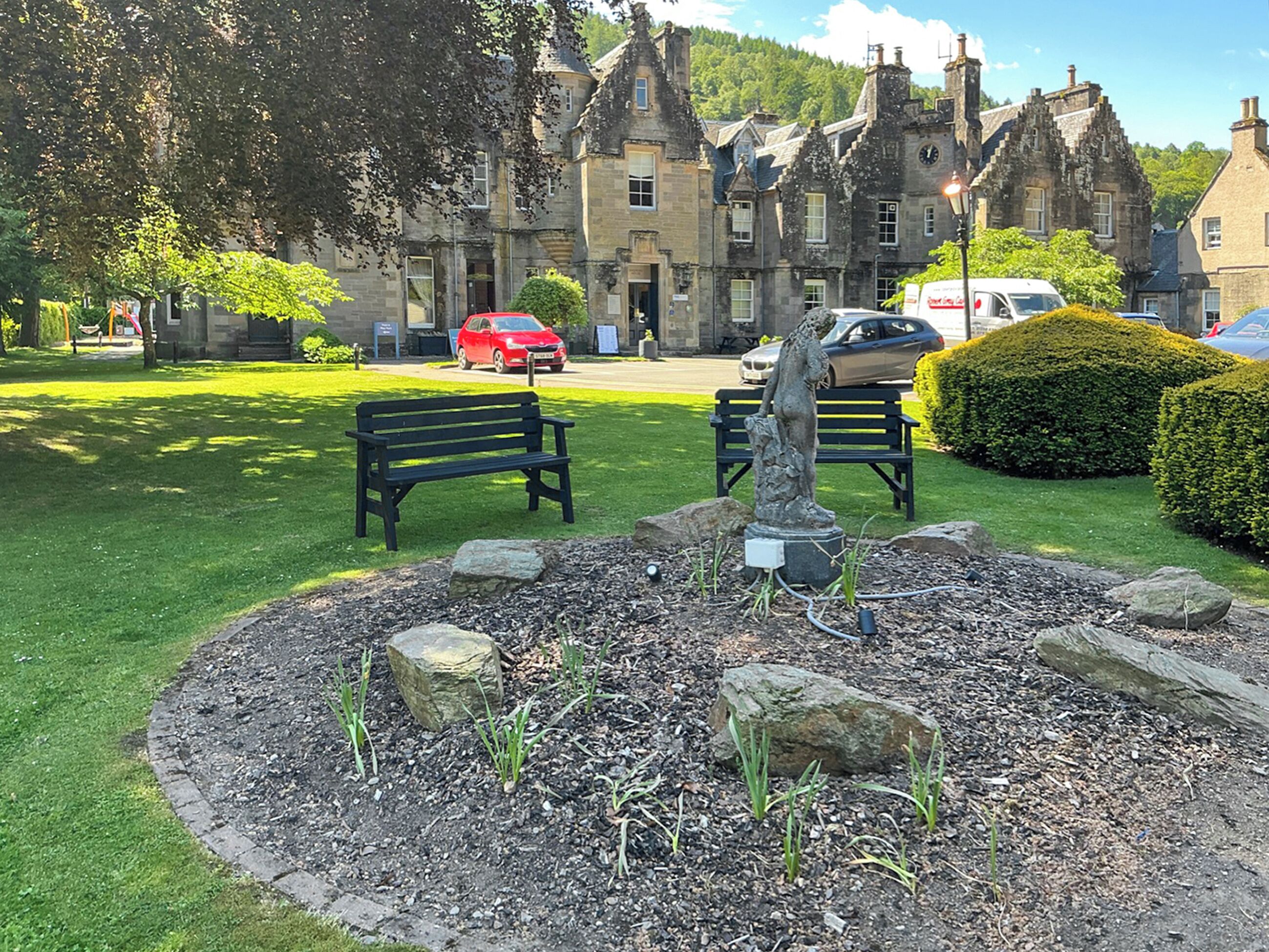 A park with benches, a statue, and a building in the background.. 3 bedroom accommodation in Dunkeld
