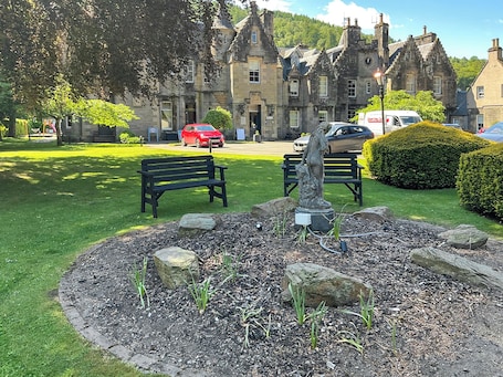 A park with benches, a statue, and a building in the background.. 3 bedroom accommodation in Dunkeld