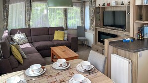Un salon chaleureux avec un canapé, une table à manger dressée pour le thé, un téléviseur et une cheminée.