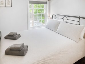 Ein Schlafzimmer mit einem Bett, Kissen, einem Fenster und Blick auf Grün.