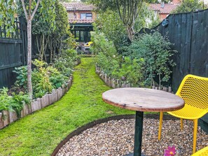 A garden with a pathway, a round wooden table, and a yellow chair. - 2 bedroom accommodation in Wenhaston (Wenhaston)