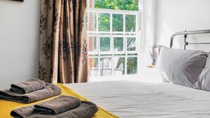 Ein Hotelzimmer mit Bett, einem Fenster mit Vorhängen und einem gelben Handtuch auf dem Boden.