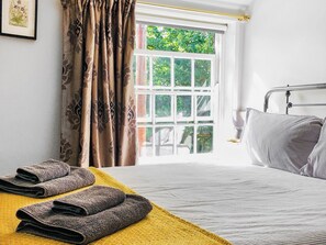 A hotel room with a bed, a window with curtains, and a yellow towel on the floor. - 2 bedroom accommodation in Wenhaston (Wenhaston)