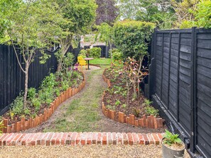 Ein Gartenpfad mit Holmkanten, einer Ziegelkante und einem kleinen Tisch mit Stuhl.