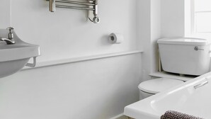 Ein Badezimmer mit weißem Waschbecken, Toilette und Handtuchhalter.