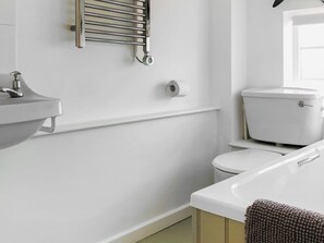 A bathroom with a white sink, toilet, and a towel rack. - 2 bedroom accommodation in Wenhaston (Wenhaston)