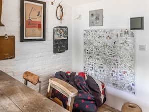 A room with a white brick wall, a framed lamp, a map, a wooden chair, and a bench. - 2 bedroom accommodation in Wenhaston (Wenhaston)