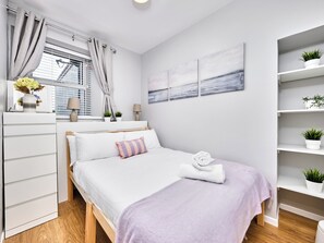 Ein modernes Schlafzimmer mit Bett, Nachttischen, einem Fenster mit Vorhängen, einem an der Wand befestigten Regal mit Pflanzen und einem Gemälde.