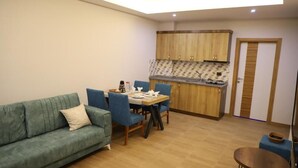 Un espacio habitable compacto con sofá, mesa de comedor, sillas, kitchenette y una pequeña mesa redonda.