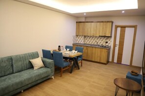 Um espaço compacto com sofá, mesa de jantar, cadeiras, cozinha compacta e uma pequena mesa redonda.
