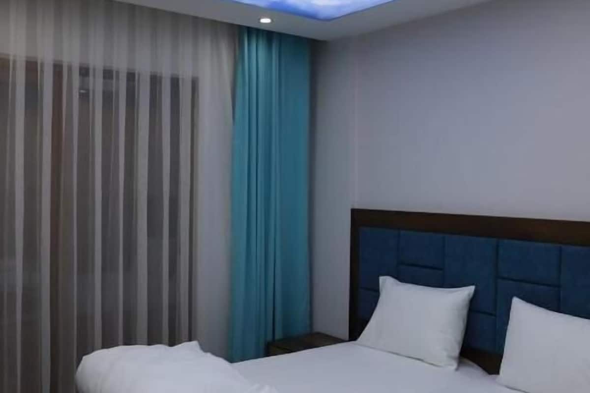 Habitación de hotel con cama, cortinas y techo decorado con un diseño de nubes.