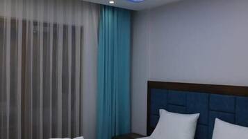 A hotel room with a bed, curtains, and a ceiling with a cloud design.