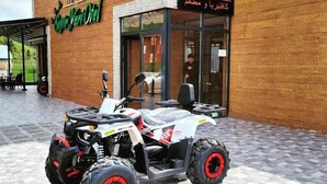 Un edificio de madera con un letrero de café y un vehículo de cuatro ruedas estacionado afuera.