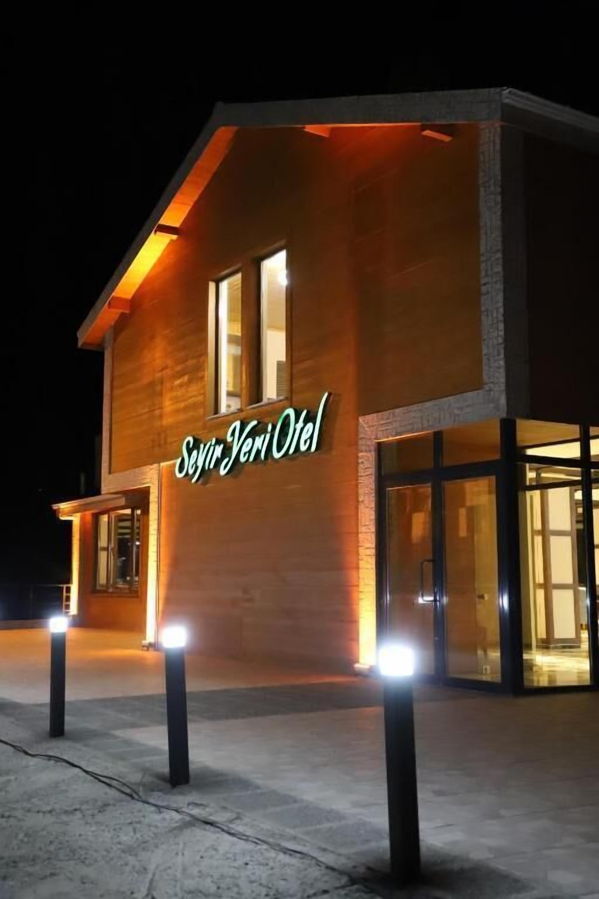 Un hotel moderno con una segnaletica ben visibile, un ingresso illuminato e una vista chiara degli interni grazie alle vetrate.