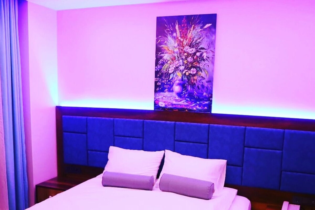 Una habitación de hotel con una cama, una mesita de noche, un teléfono y un cuadro colgado en la pared.