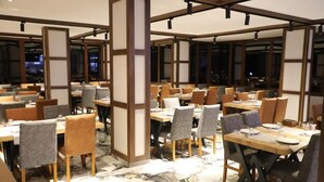 Un restaurante con varias mesas y sillas, vigas de madera y piso de baldosas.