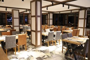 Un restaurant amb diverses taules i caires, bigues de fusta i un paviment de rajoles.