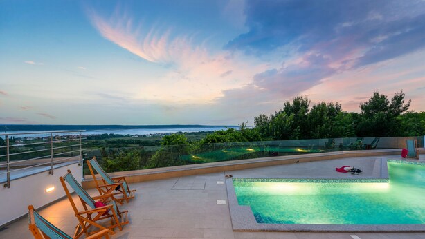 Ein Pool auf dem Dach mit Liegestühlen und Blick auf die Landschaft.