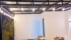Une pièce avec un plafond haut, des poutres apparentes et une table entourée de quatre chaises.