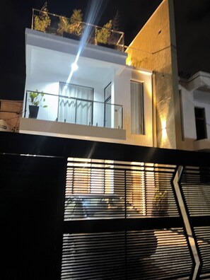 Edifici modern amb un balcó, una planta en test i una escala.