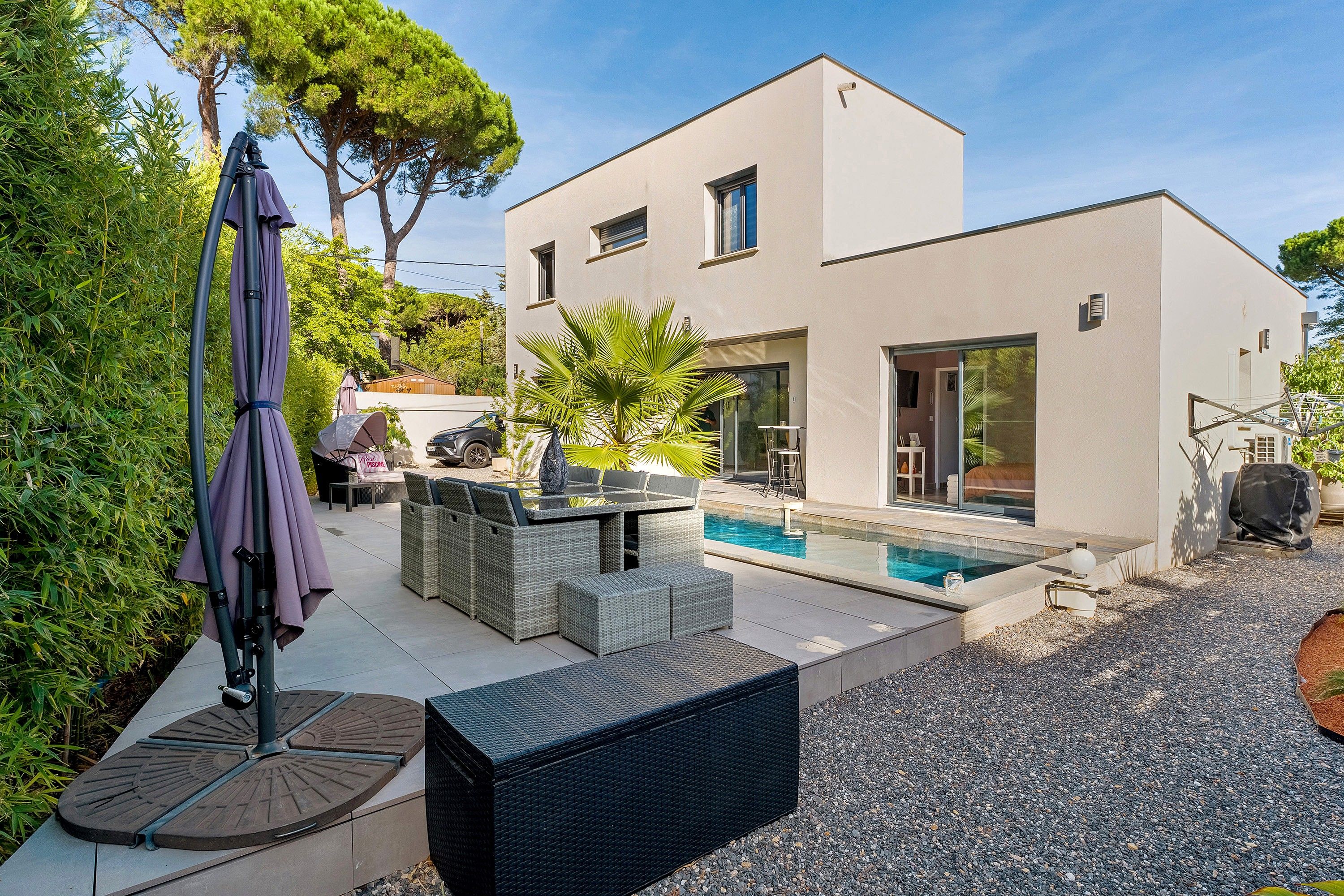 A modern house with a swimming pool, outdoor furniture, and a patio area.