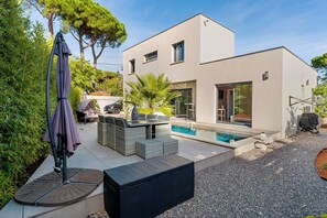 Una casa moderna con piscina, mobiliario de exterior y una zona de patio.