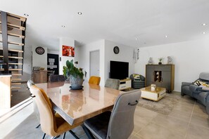 Ein modernes Wohnzimmer mit Essbereich, einem Flachbildfernseher und einer Couch.