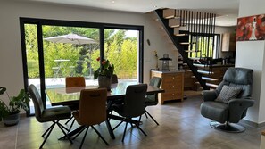 En moderne stue med spiseområde, store vinduer og en trappe.