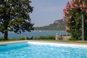 Ein Schwimmbad mit Blick auf einen See und Hügel.