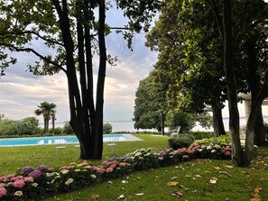 A pool area with chairs, a lawn, and a variety of flowers. - Apartment 'Appartamento Alessandra' with Lake View, Wi-Fi and Air Conditioning (Garda)