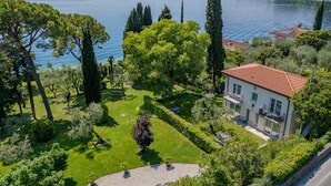 Una casa con techo rojo, rodeada por un jardín cuidado y vistas a un lago.
