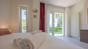 Ein Schlafzimmer mit einem großen Bett, einem Fenster und Blick ins Freie.