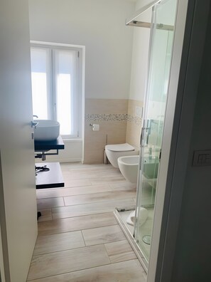 A modern bathroom with a large vessel sink, toilet, and glass shower enclosure. - Apartment 'Flora' with Lake View, Wi-Fi and Air Conditioning (Garda)