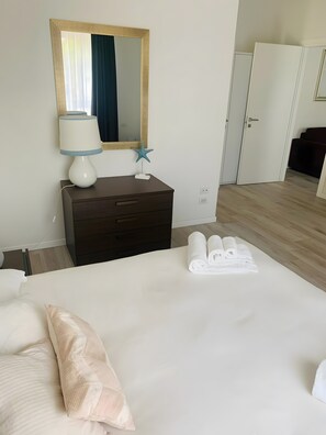 A hotel room with a bed, a dresser, a mirror, a star decoration, and a set of towels. - Apartment 'Flora' with Lake View, Wi-Fi and Air Conditioning (Garda)