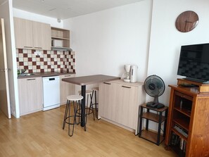 Eine moderne Küche mit Kaffeemaschine, einem Ventilator und einem Fernseher auf einem Holzboden.