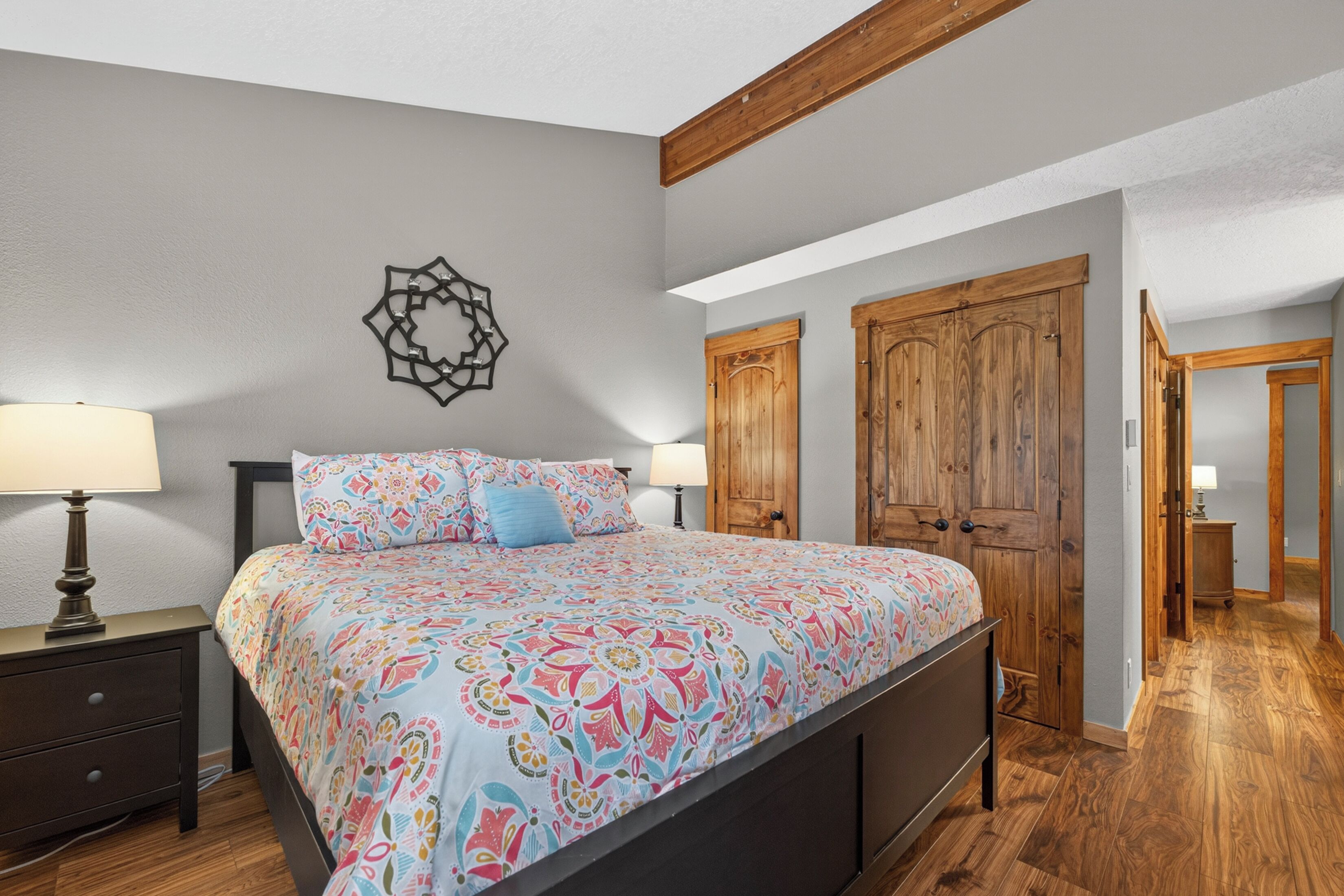 Un dormitorio con cama, mesitas de noche, un armario de madera y un adorno en la pared.