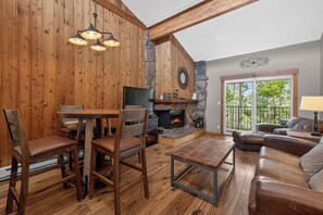 A wooden interior with a fireplace, a dining area, and a seating area with a view. - Spacious, renovated 2 bedroom, vaulted ceilings, private deck (Winter Park)