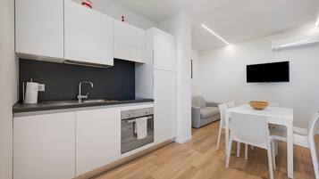 A modern kitchen with white cabinets, a built-in oven, and a grey countertop.