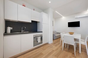 A modern kitchen with white cabinets, a built-in oven, and a grey countertop.