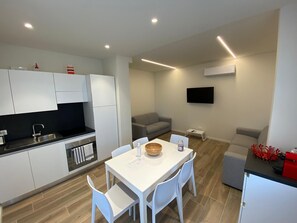 A modern kitchen with white cabinets, a black countertop, and a dining area with a white table and chairs. - Apartment 'Matilde' with Lake View, Wi-Fi and Air Conditioning (Garda)