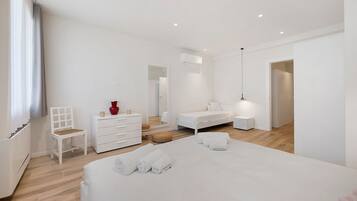 A modern bedroom with a bed, a chair, a dresser, and a bedside table.