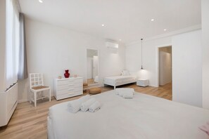 A modern bedroom with a bed, a chair, a dresser, and a bedside table.