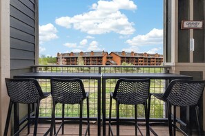 A balcony with four black chairs and a table, overlooking a building with a sign reading 'GRANBY ELEV. 7935'. - Pet friendly, private patio, lovely 2 bedroom (Granby)