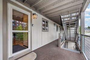 A covered corridor with a staircase, a glass door leading to a balcony, and a metal railing. - Hi Country Haus Unit 1909 Renovated 2nd floor private patio, walk to downtown WP (Winter Park)