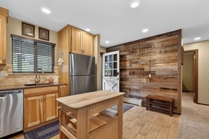 A modern kitchen with wooden cabinets, a stainless steel refrigerator, and a wooden bench. - Renovated, second floor, private patio, walk to downtown WP (Winter Park)
