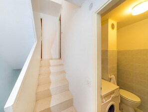 Eine Treppe zu einem Badezimmer mit Waschmaschine und Toilette.